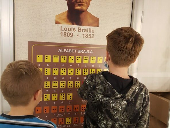 uczniowie przed tablicą z popiersiem Louisa Braille'a