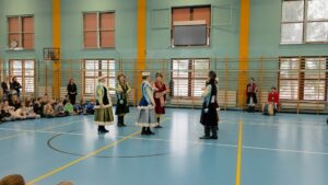 tancerze w barwnych strojach regionalnych i szlacheckich prezentują układy choreograficzne przed publicznością.